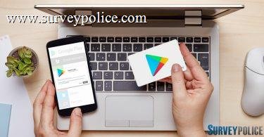 Woman holding Google Play gift card while using phone and laptop